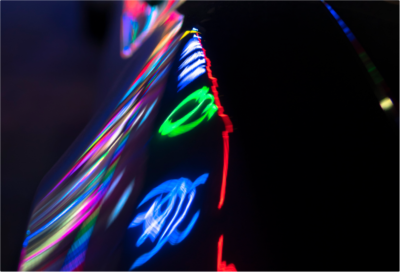 A car with neon light reflecting off of it.