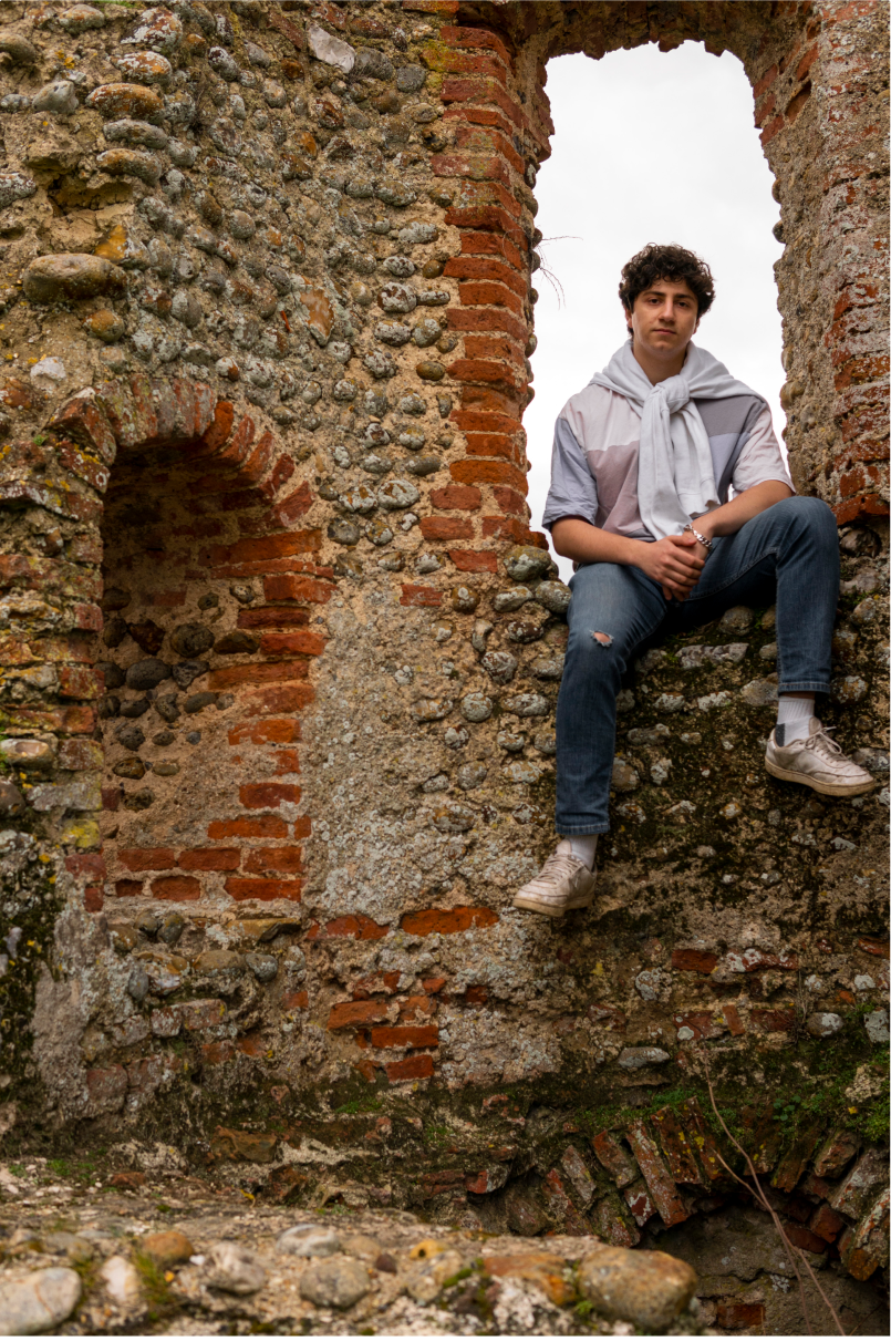 A man sitting in the window of an old castle spire.