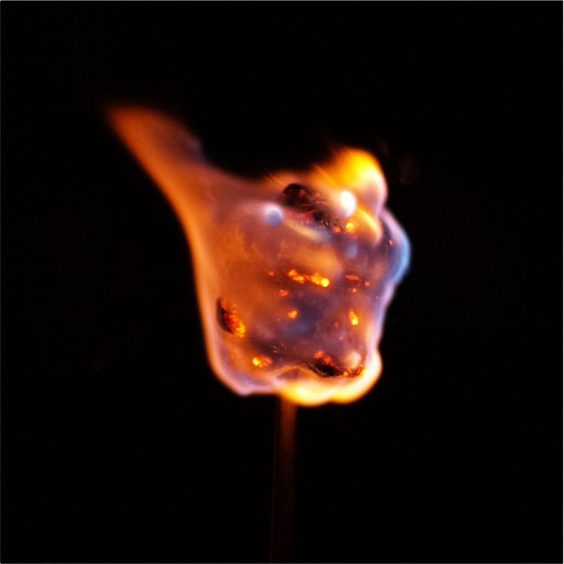 A marshmellow on a stick burning.