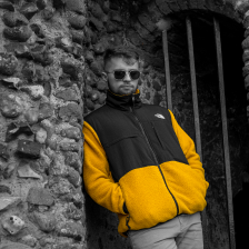 My model leaning against a cobblestone wall, edited to have only yellow saturation.