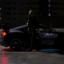 A man exiting his car on a rooftop at night.